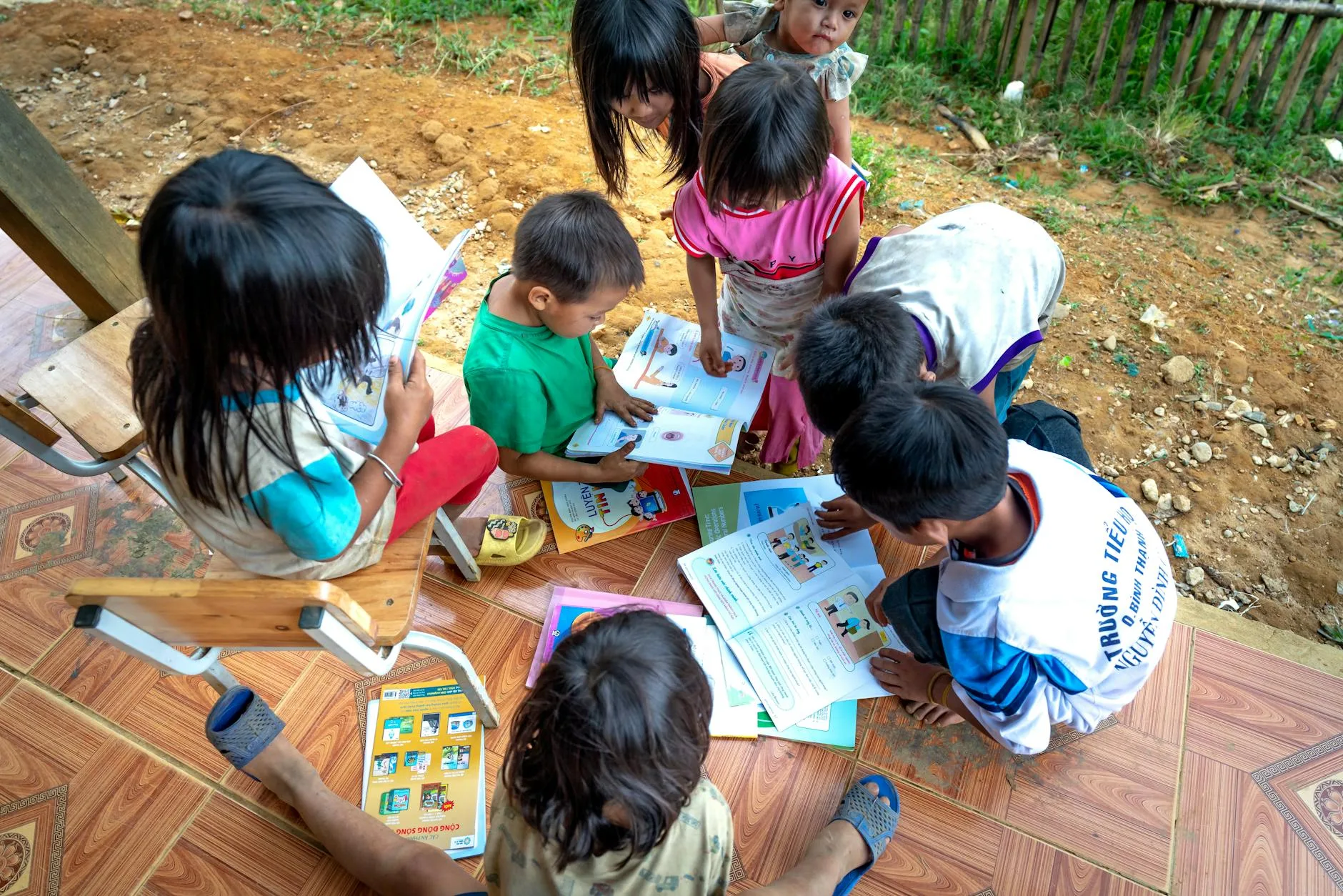 Anak usia dini membaca buku cerita bersama guru