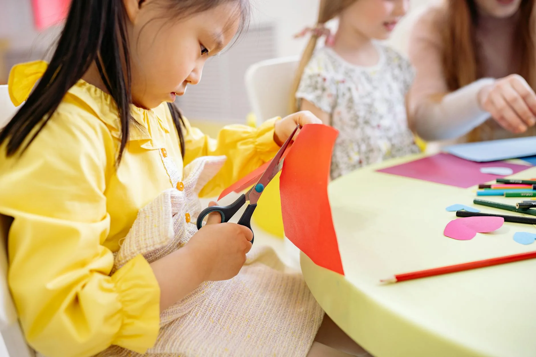 Anak TK melakukan latihan gunting kertas dengan hati-hati